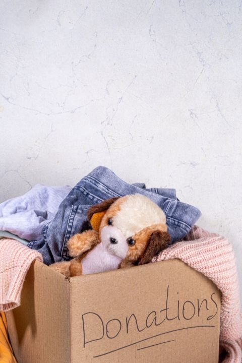 A cardboard box labeled Donations, filled with clothes and a soft toy